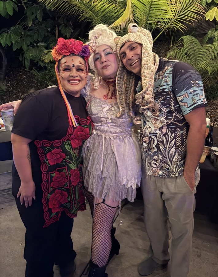 Three friends in costume posing together at a party.